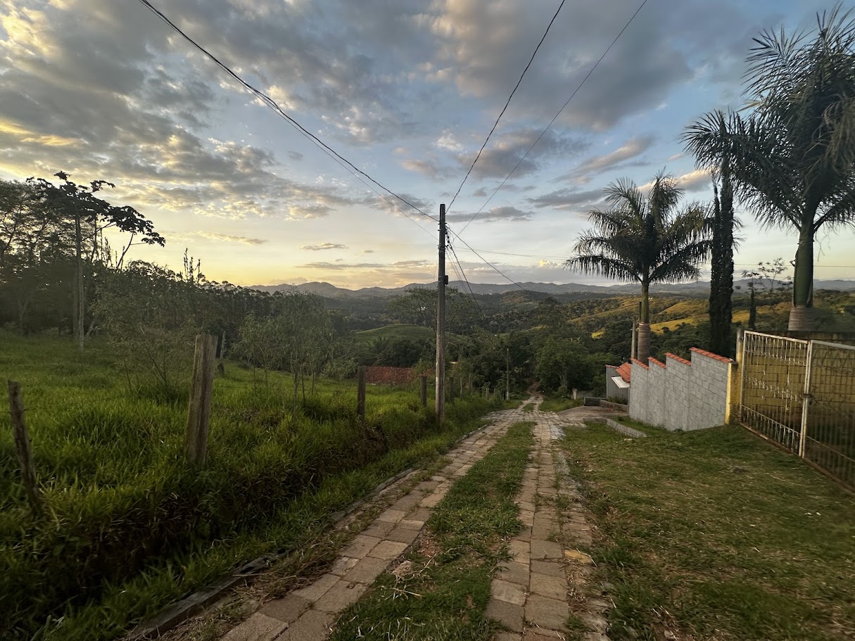 Vista atual da rua inclinada, com faixas de pavimento e áreas em terra